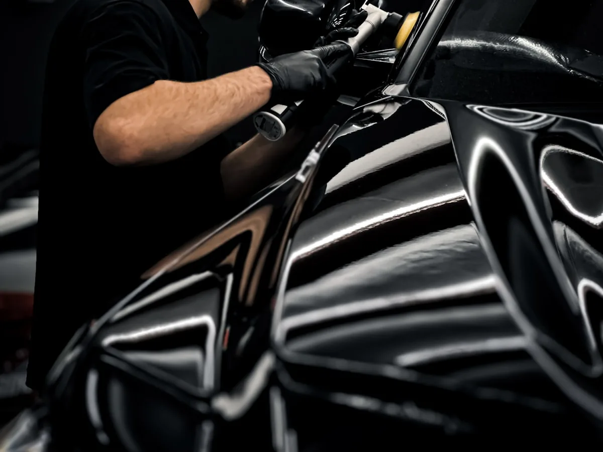 Profissional aplicando polimento e cera na lataria preta de um carro